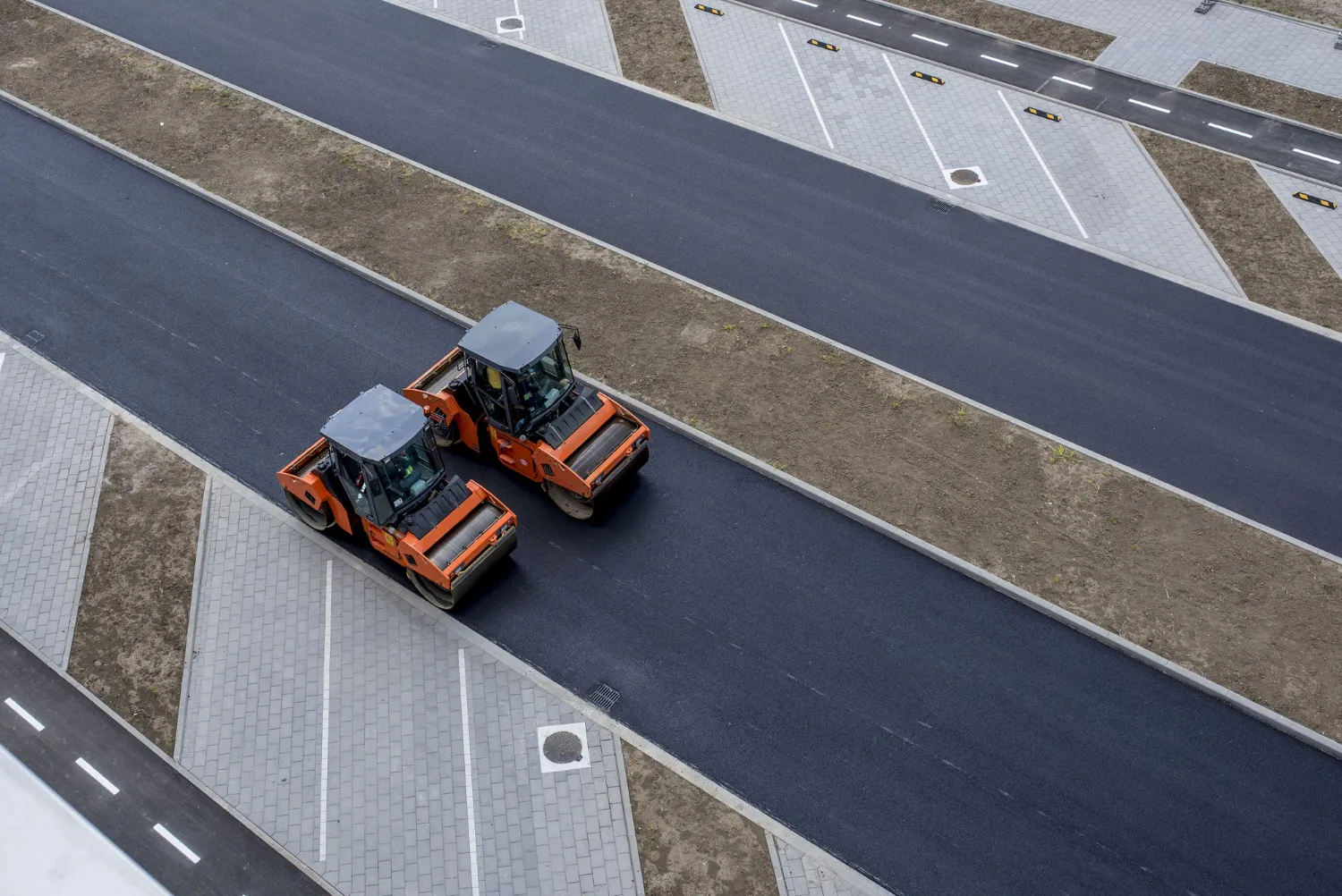 Aerial view of road rollers laying fresh asphalt — engineering projects at scale